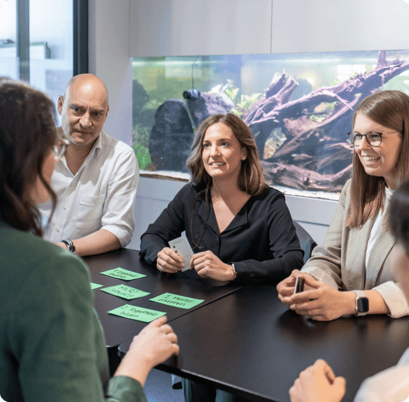 Team at a meeting table arranging green cards with individual work steps