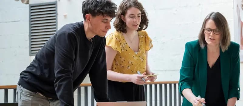 Three colleagues standing and working together at a table