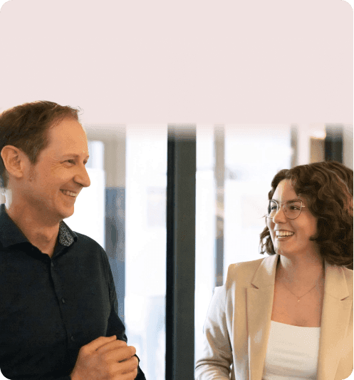 Laughing man chatting with a colleague in a beige blazer in the office