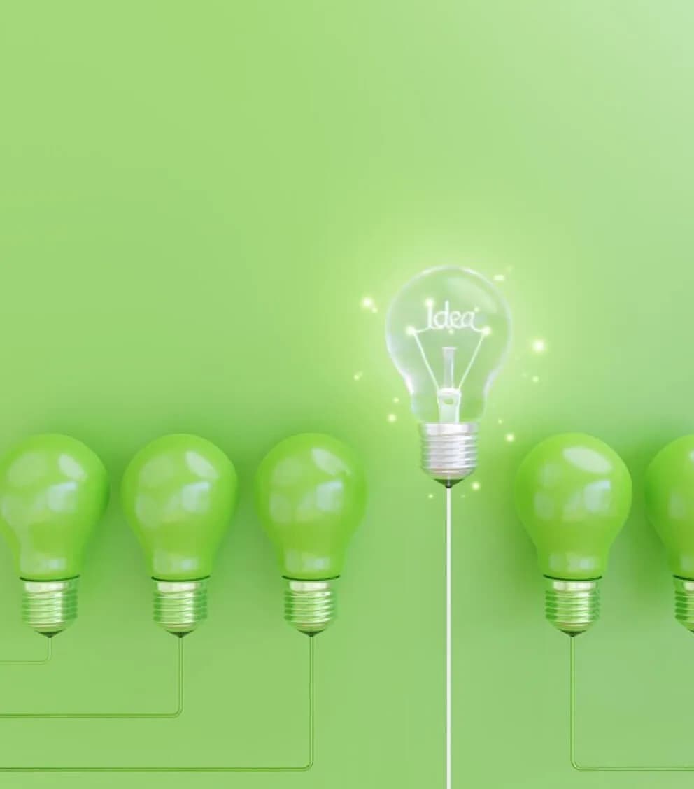 Reihe grüner Glühbirnen, eine davon leuchtet mit dem Schriftzug „Idea“
