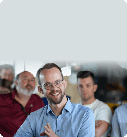Lächelnder Mitarbeiter inmitten einer Gruppe von Zuhörern