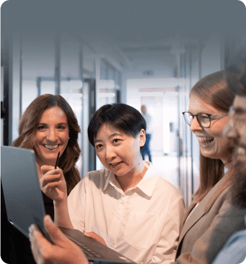 Four colleagues laughing as they look at a laptop together