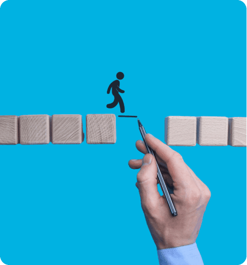 Hand drawing a line across the gap between wooden blocks so a walking figure can keep going