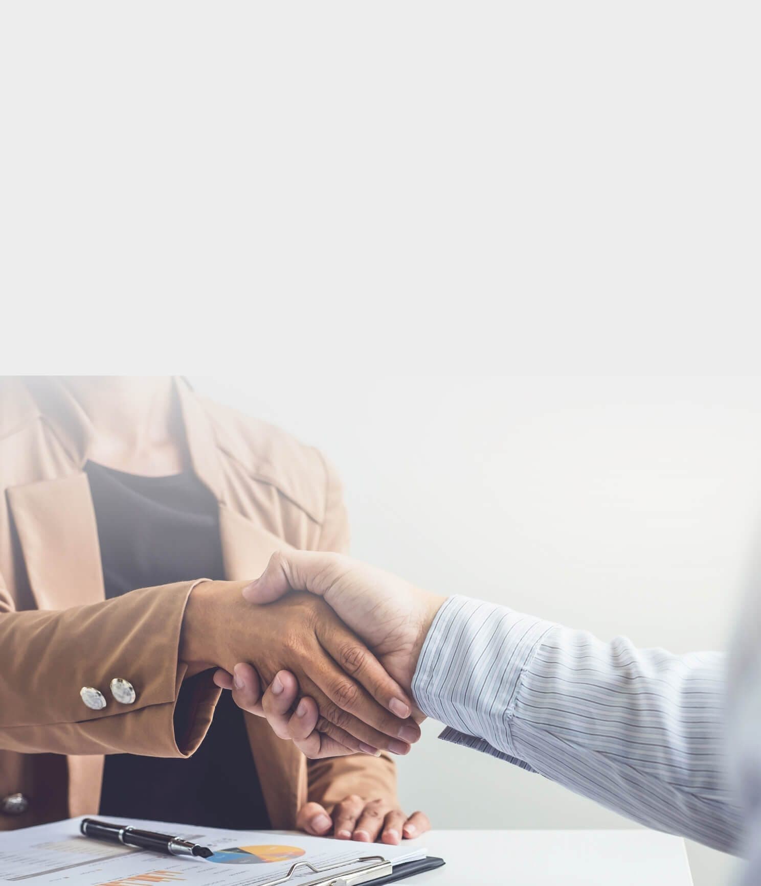 Handshake over a desk with documents
