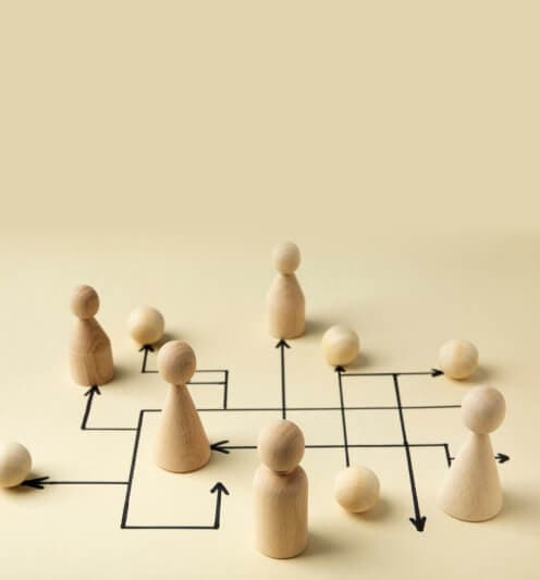 Holzfiguren auf einem Netz aus Pfeilen als Sinnbild für feste Strukturen und Abläufe in der Organisation