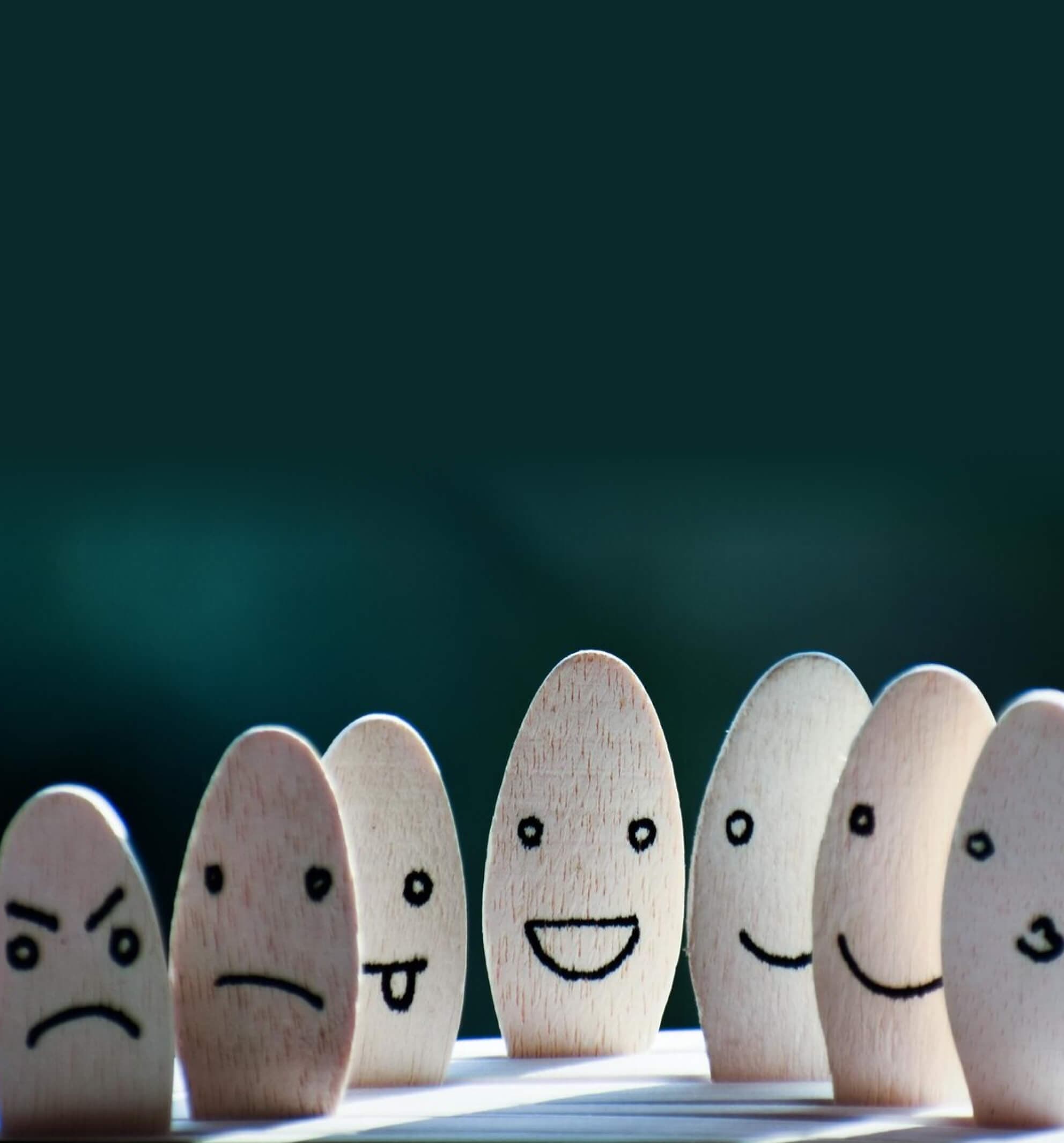 Wooden figures with painted faces showing emotions from angry to happy