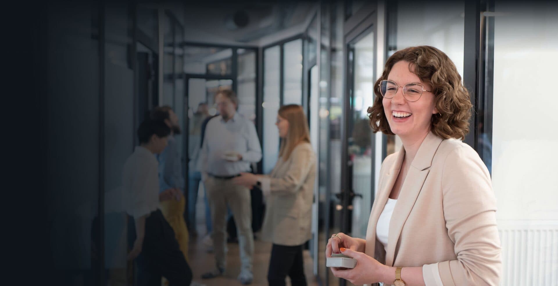 Laughing CPC employee in the office, with colleagues talking in the background