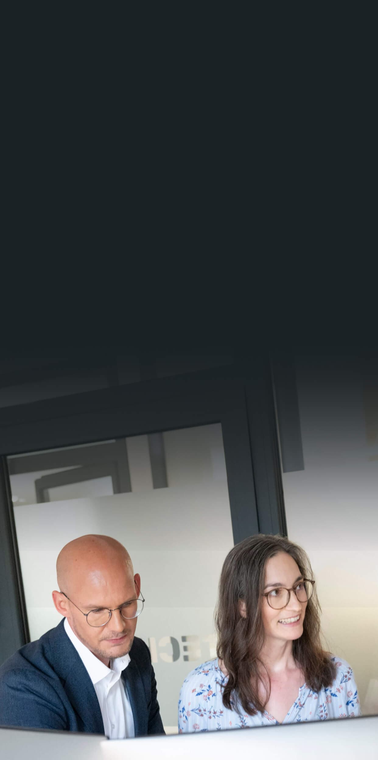 Beratungsteam blickt im Büro gemeinsam auf einen Monitor und bespricht den KI-Einsatz