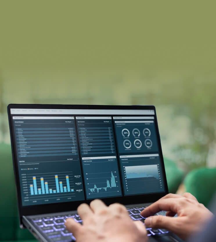 Laptop mit Analyse-Dashboard aus Balken- und Liniendiagrammen, davor tippende Hände