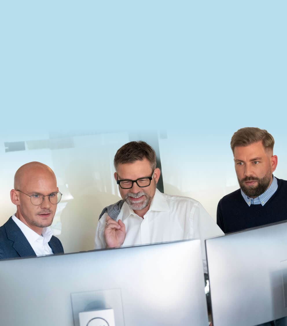 Three consultants looking at two monitors together, aligning on a shared target picture