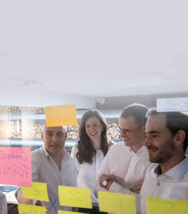Team plant an einer Glaswand mit Haftnotizen die Roadmap der Veränderung