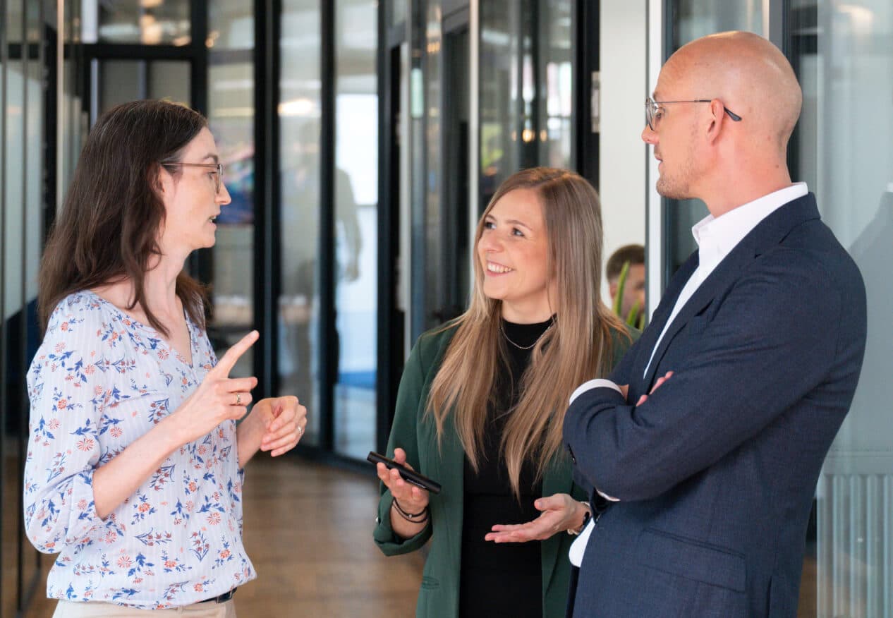 Three colleagues talking in an office corridor, exchanging views on change in the organisation