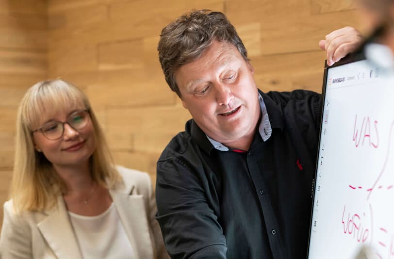 Consultant explaining the change process to a colleague on a digital whiteboard