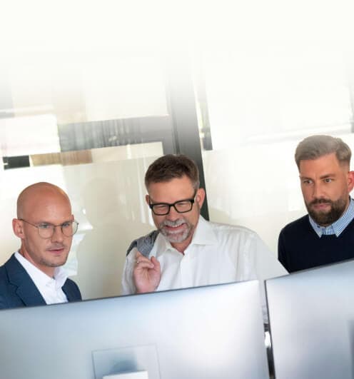 Three consultants trying out applications together on two monitors