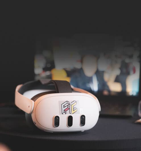 White VR headset on a table, with a screen behind it