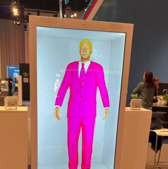 Holographic figure in a pink suit inside a display column at a trade fair