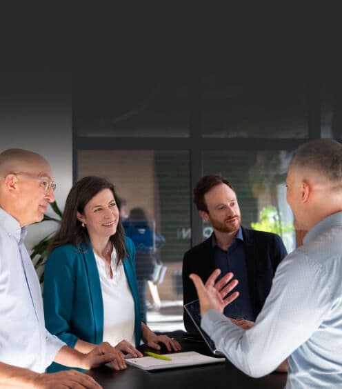 Consultant gesturing as he explains an approach to three listeners at a meeting table