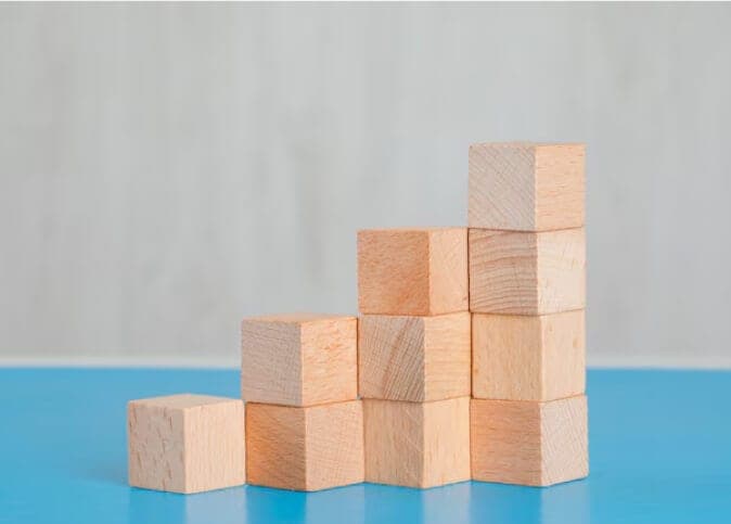 Wooden blocks stacked into a staircase on a blue surface