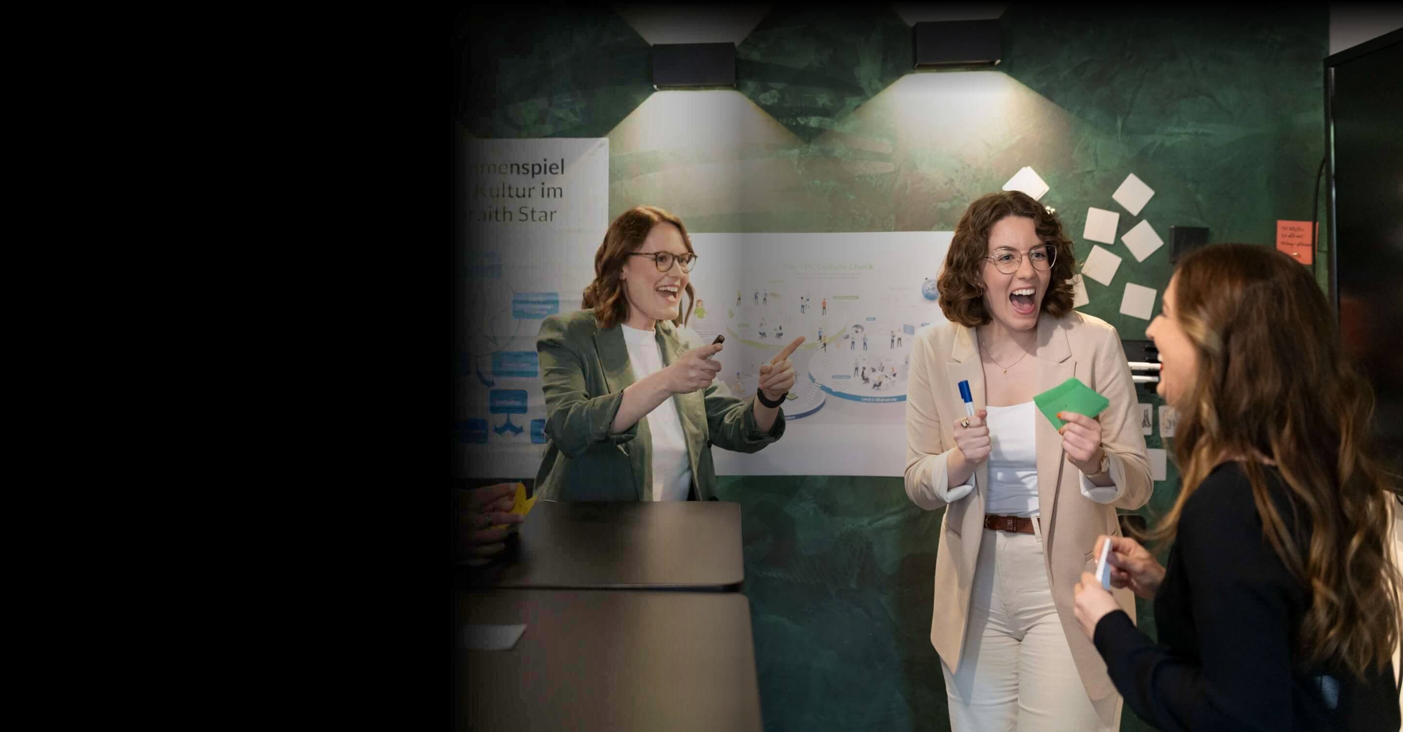 Three consultants laughing in a workshop in front of posters on the Galbraith Star and the CPC Culture Check