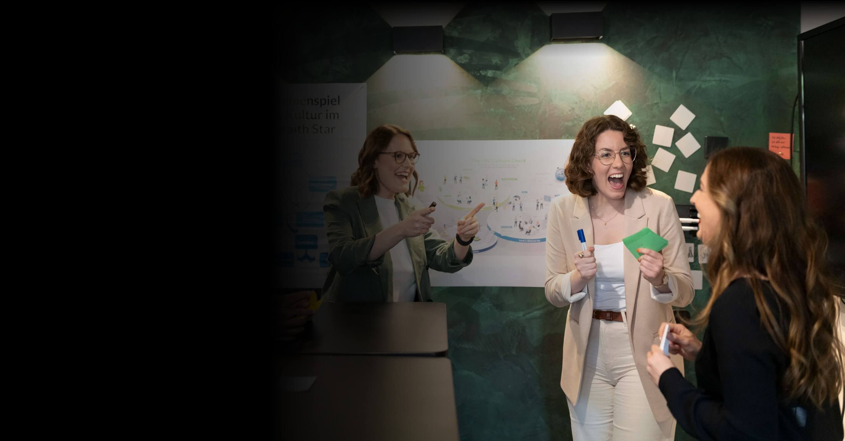 Drei Beraterinnen lachen im Workshop vor Postern zum Galbraith Star und zum CPC Culture Check