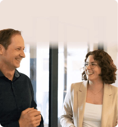 Kollege und Kollegin lachen sich im Büro an