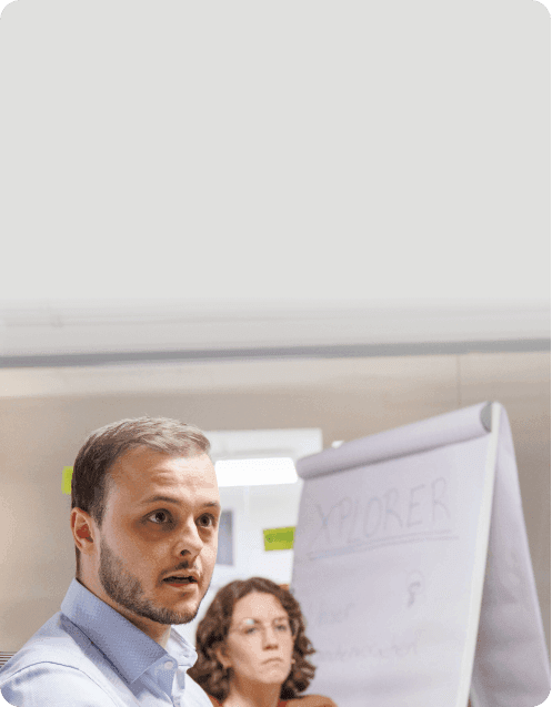 Teilnehmer spricht im Workshop, hinter ihm eine Kollegin und ein Flipchart