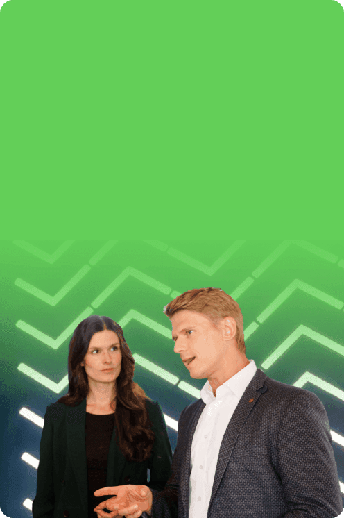 Two consultants, a woman and a man, talking in front of a glowing green background