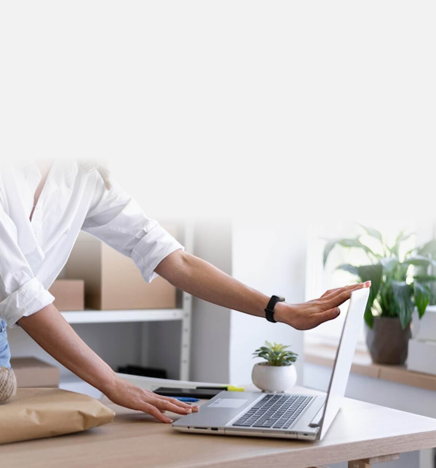 Person at a desk pointing at a laptop