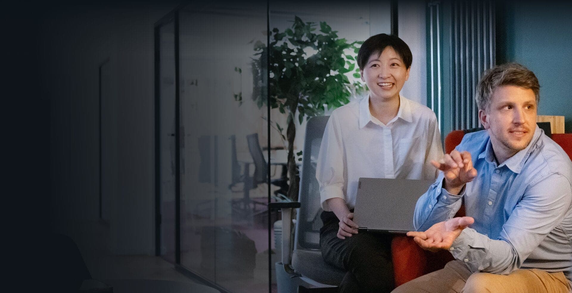 Consultant holding a laptop and a gesturing colleague discussing a change management initiative