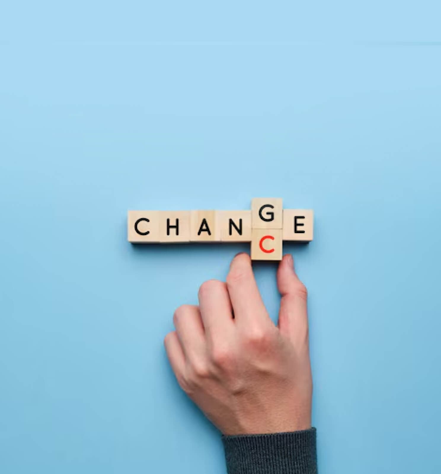 Hand arranging letter cubes to spell the word change