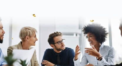 Three colleagues in conversation at a meeting table