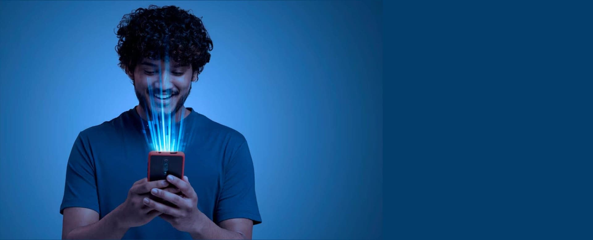Junger Mann blickt lächelnd auf sein Smartphone, aus dem Lichtstrahlen aufsteigen