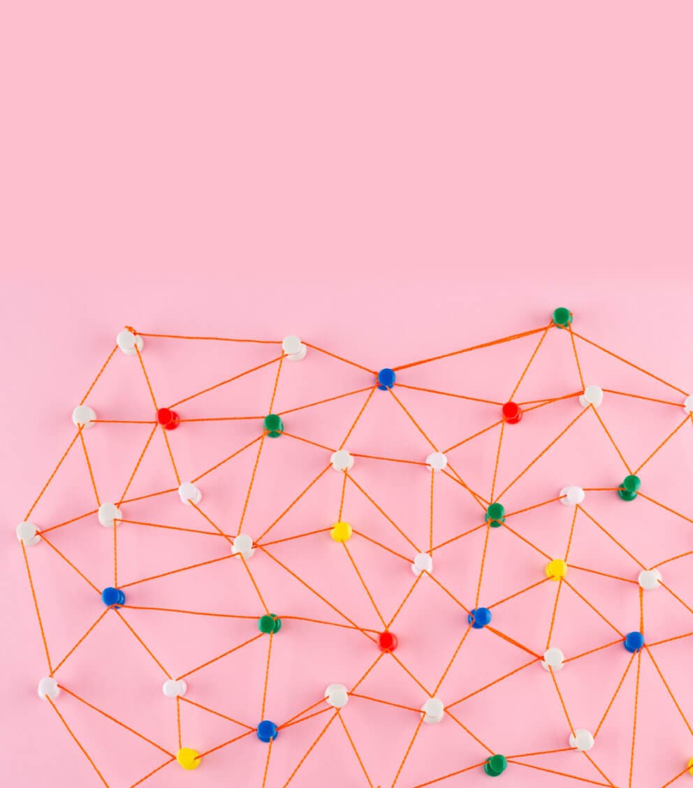 Colorful pins connected by orange thread into a network