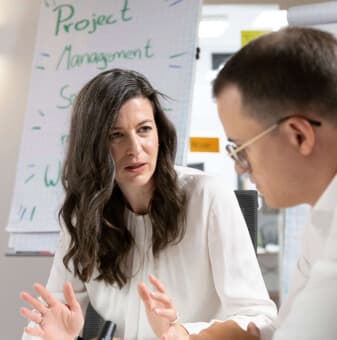 Beraterin im Gespräch vor einem Flipchart zum Thema Projektmanagement