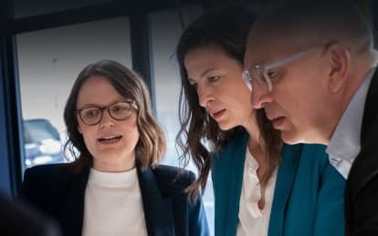 Three people in focused conversation at a meeting table