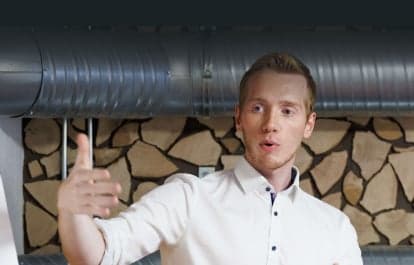 Berater im weißen Hemd erklärt gestikulierend vor einer Wand aus Holzscheiten