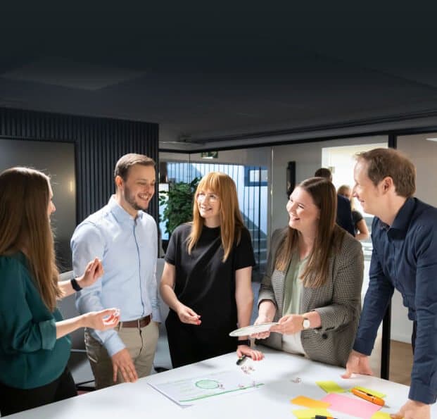 Team laughing around a table with sticky notes and dice, working on ideas in a workshop