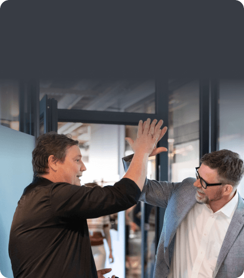 Two men high-fiving in an office