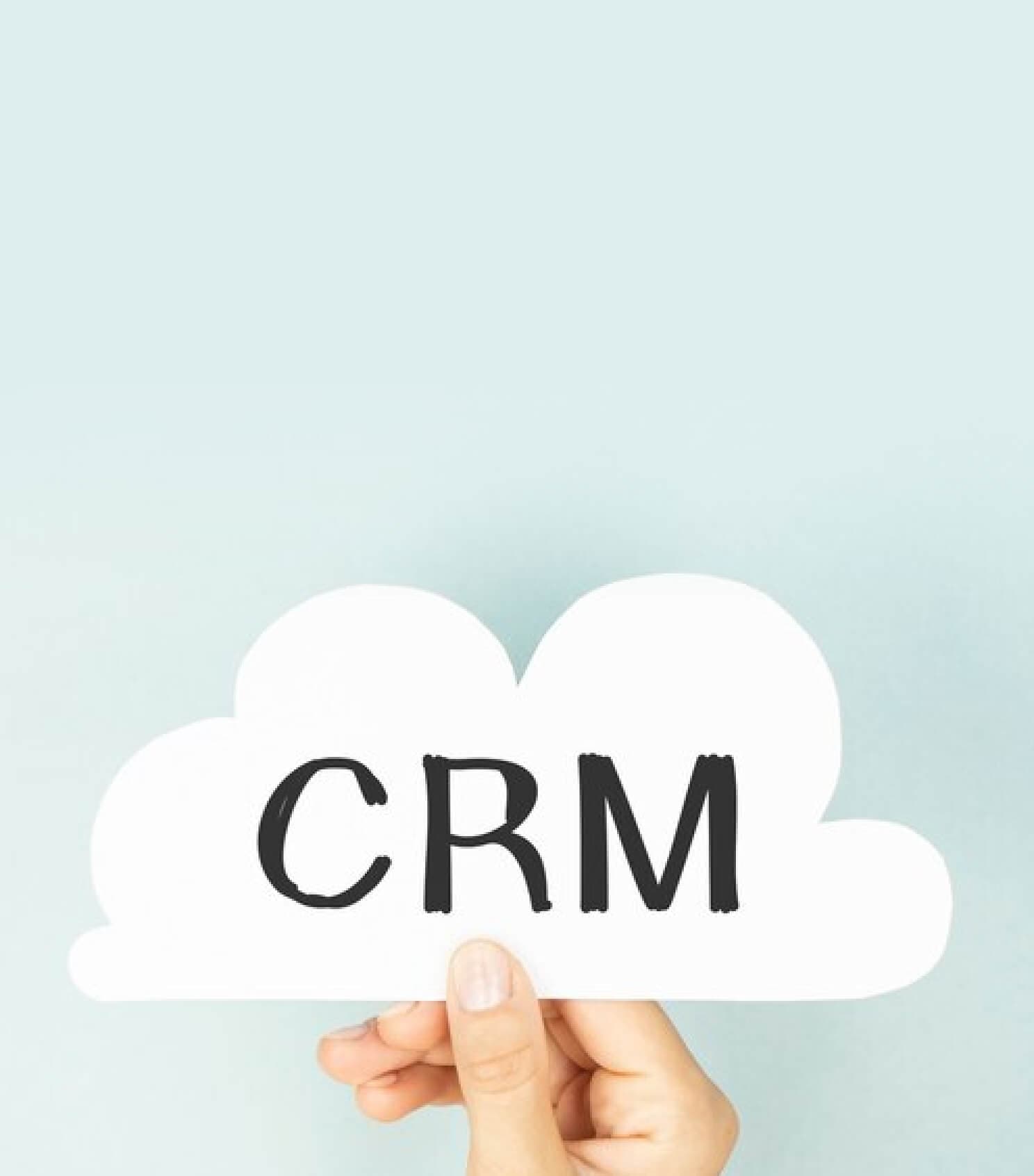 Hand holding a cloud-shaped sign reading CRM