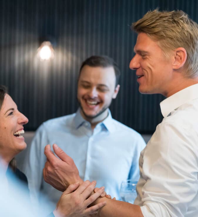 Three colleagues laughing, two of them shaking hands