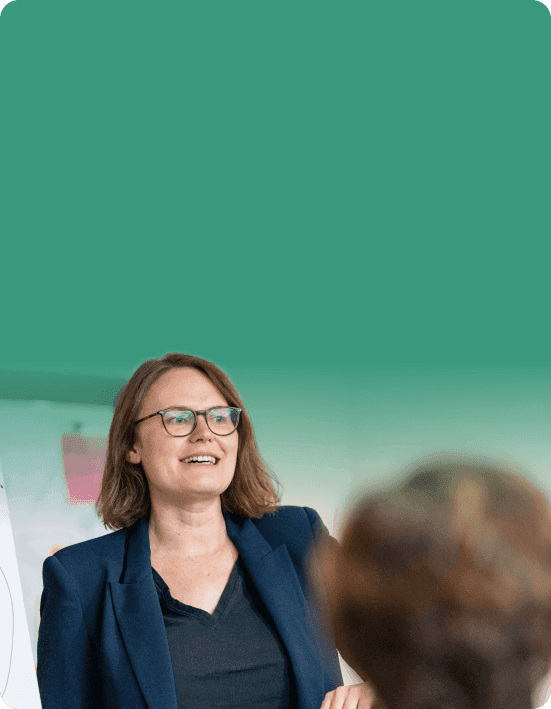 Trainer in a navy blazer smiling as she speaks in front of a flipchart