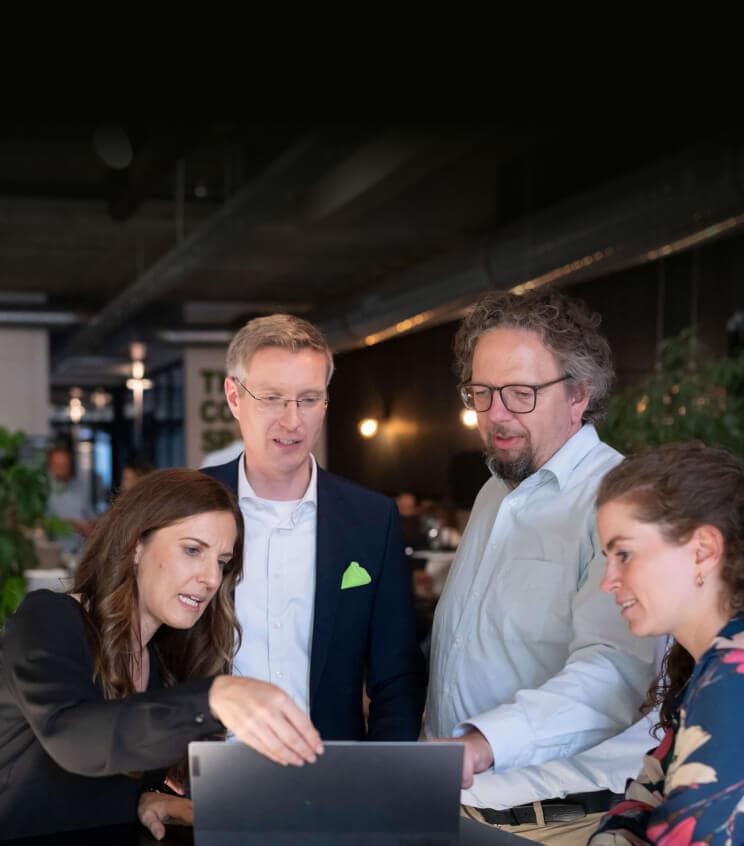 Four colleagues leaning over a laptop together