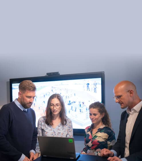 Team working at a laptop in front of a large screen showing an illustration