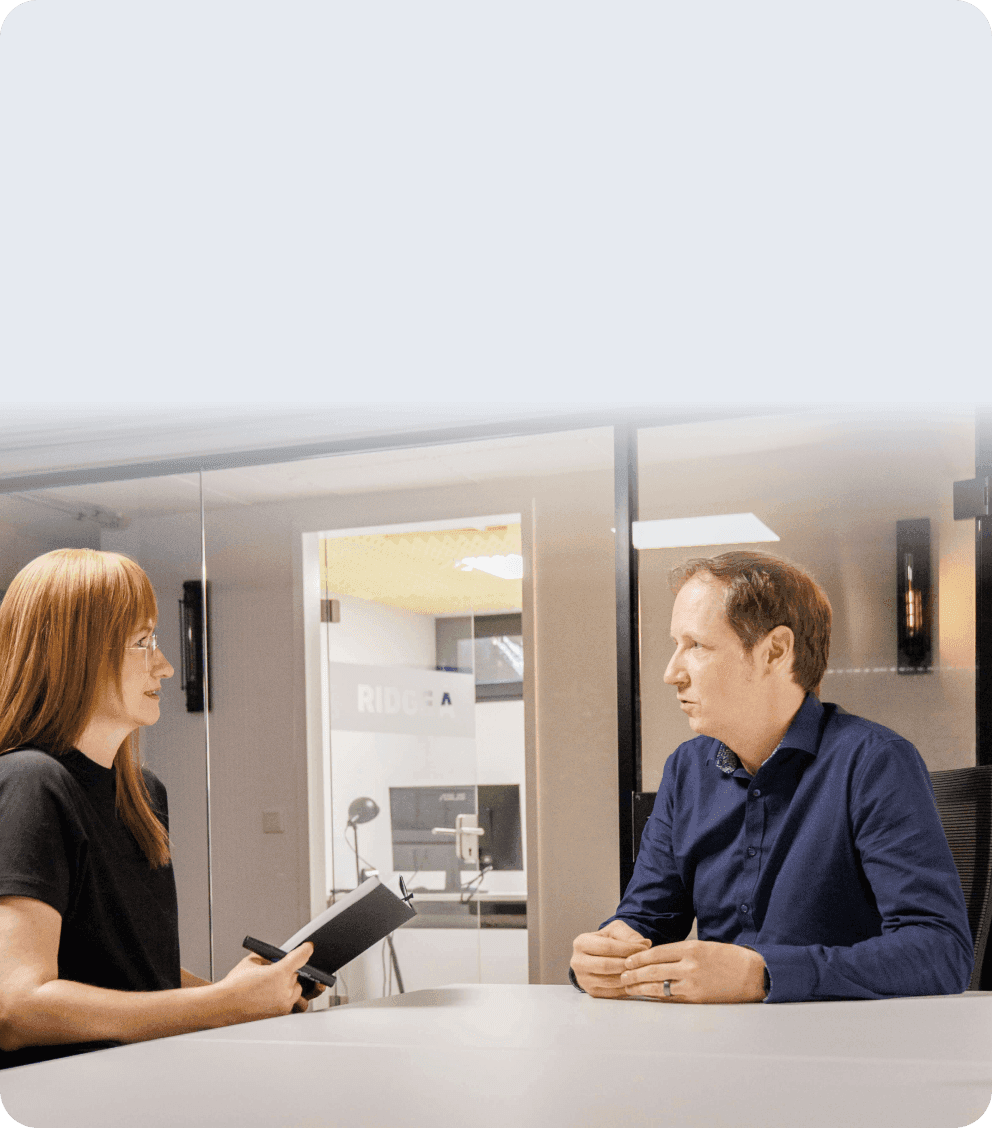 Consultant with a notebook in conversation with a man at a meeting table