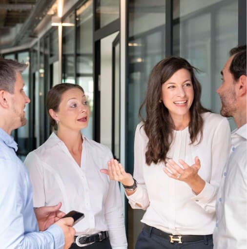 Four businesspeople in lively conversation in an office corridor