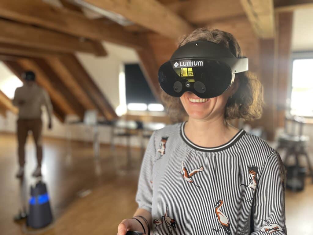 Lachende Frau mit VR-Brille bei einem Virtual-Reality-Workshop im Dachgeschoss