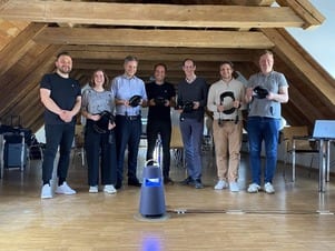Virtual Reality: Sieben Personen halten VR-Brillen in der Hand und posieren gemeinsam in einem hellen Dachgeschossraum – Change meets Virtual Reality